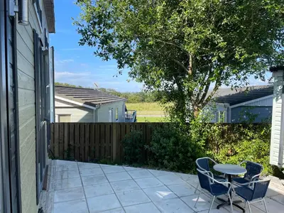 a patio with a table and chairs and a fence at Derw View Green Lodge in Aberystwyth