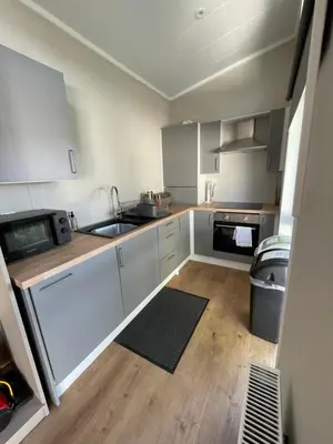 a small kitchen with white cabinets and a sink at Derw View Green Lodge in Aberystwyth