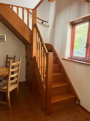 a wooden staircase in a room with a table and a window at Frog Cottage, Ludlow - a charming townhouse for 4 in Ludlow