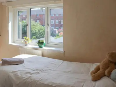a teddy bear sitting on a bed in front of a window at Georgian Terrace Town House in Mid Wales in Newtown