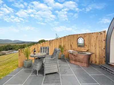 a patio with a table and chairs and a tub at Dyfi - Uk46064 in Llancynfelyn