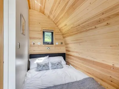 a bed in a room with a wooden ceiling at Dyfi - Uk46064 in Llancynfelyn