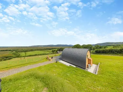 a large building in a field with a person standing in the grass at Leri - Uk46065 in Llancynfelyn