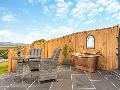 a patio with a tub and chairs and a fence at Leri - Uk46065 in Llancynfelyn