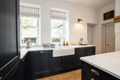 a kitchen with black cabinets and a sink at Haulfryn in Barmouth