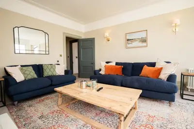 a living room with blue couches and a wooden coffee table at Haulfryn in Barmouth