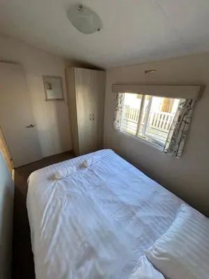 a bedroom with a large bed and a window at Caravan in Barmouth in Llanddwywe