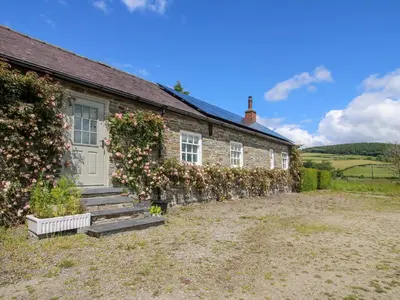 a brick house with roses growing on the side of it at The Mytton at Mill Barn in Craven Arms
