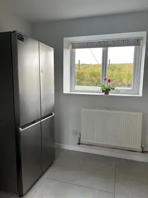 a kitchen with a stainless steel refrigerator and a window at Cosy countryside cottage in Aberystwyth