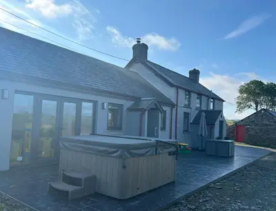 a house with a large hot tub in front of it at Cosy countryside cottage in Aberystwyth