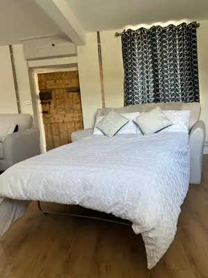 a bedroom with a large bed with white sheets and pillows at Cosy countryside cottage in Aberystwyth