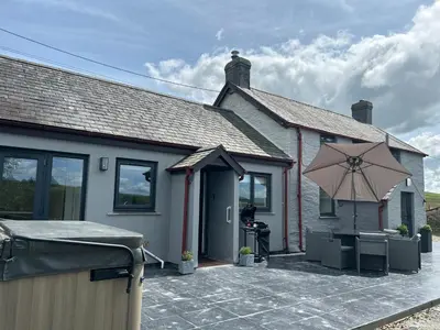 a house with a patio with an umbrella at Cosy countryside cottage in Aberystwyth