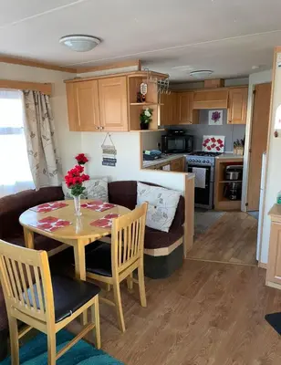 a kitchen and living room with a table and a couch at Lovley 3 bedroom Static Caravan in Clarach Bay in Aberystwyth