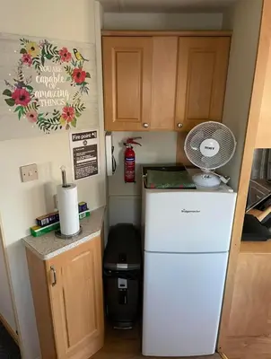 a small kitchen with a refrigerator and a fan at Lovley 3 bedroom Static Caravan in Clarach Bay in Aberystwyth
