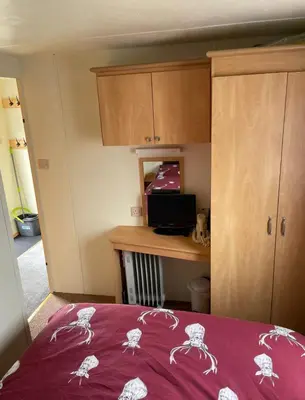 a bedroom with a bed and a desk and cabinets at Lovley 3 bedroom Static Caravan in Clarach Bay in Aberystwyth