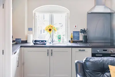 a kitchen with a sink and a vase with a sunflower at Sunday School House in Shrewsbury