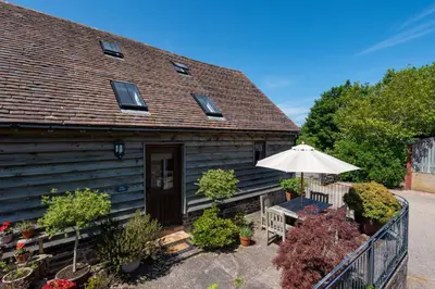 a house with a bench and an umbrella at The Barn at Middle Farm and Cottages in Picklescott