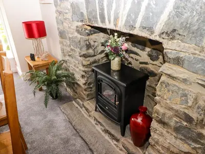 a stone fireplace with a stove in a room at Morva in New Quay