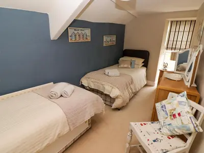 a bedroom with two beds and a chair in it at Morva in New Quay