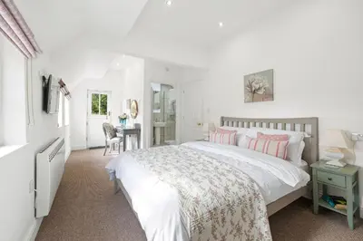 a white bedroom with a bed and a desk at Flower Cottage by Ludlow Castle with Onsite Parking in Ludlow