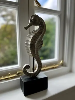 a statue of a seahorse on a stand in a window at Flower Cottage by Ludlow Castle with Onsite Parking in Ludlow