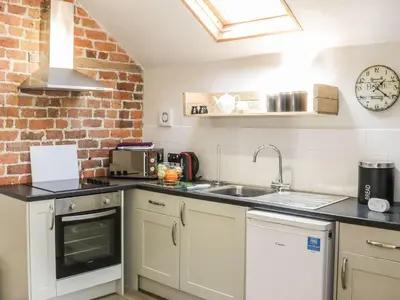 a kitchen with a sink and a brick wall at Orchard Cottage in Newtown