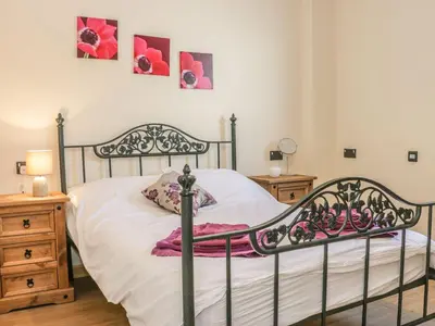 a bedroom with a bed with white sheets and pink flowers at Orchard Cottage in Newtown