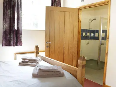 a bedroom with a shower and a bed with towels at Woodside Cottage in Newtown