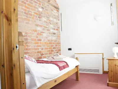 a bedroom with a bed with a brick wall at Woodside Cottage in Newtown