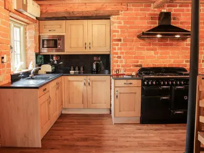 a kitchen with wooden cabinets and a brick wall at Garden Cottage in Newtown