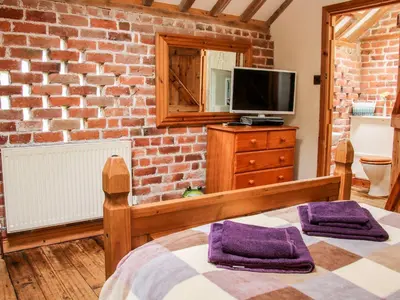 a brick walled bedroom with a bed and a television at Garden Cottage in Newtown