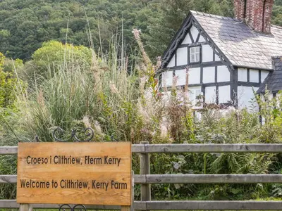 a sign in front of a house with a garden at Garden Cottage in Newtown