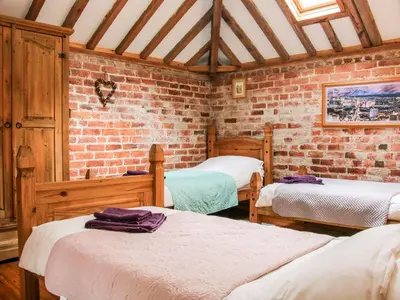 a room with three beds and a brick wall at Garden Cottage in Newtown