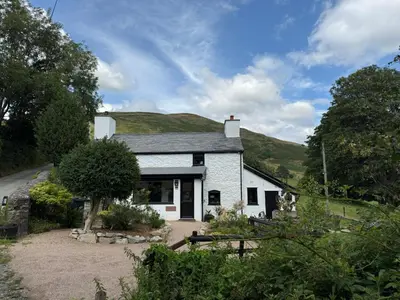 a white house with a hill in the background at Maengwynedd, Llanrhaeadr Ym Mochnant in Oswestry