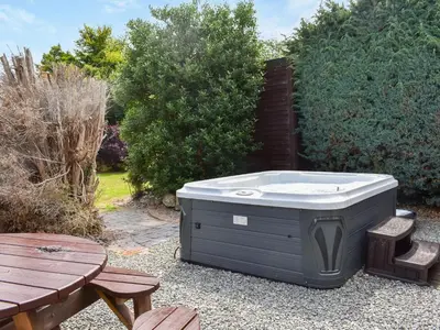 a hot tub sitting on the ground next to a picnic table at Tan Y Gaer in Aberystwyth