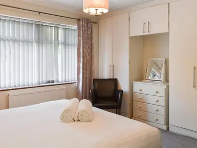 a bedroom with a bed and a chair and a window at Tan Y Gaer in Aberystwyth