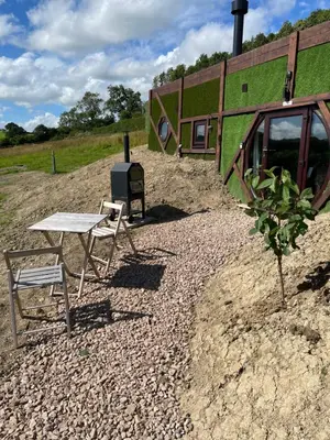 a picnic table and two chairs in front of a building at Acorn Warren in Welshpool