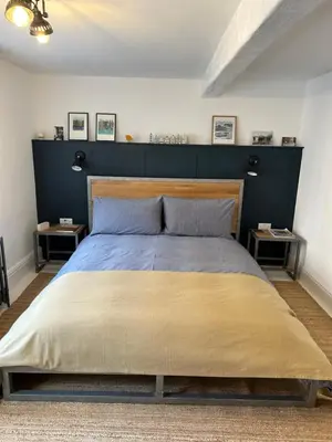 a bedroom with a large bed with a blue headboard at The Hat Works in Ludlow