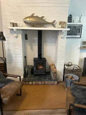 a living room with a fireplace with a fish on a shelf at The Hat Works in Ludlow