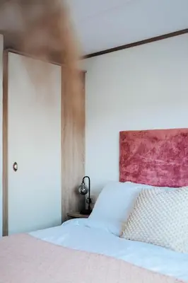 a bedroom with a white bed with a pink headboard at Foxglove Lodge in New Quay