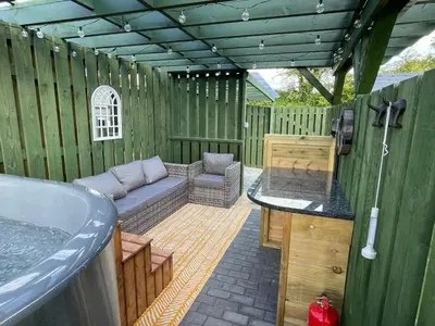 a outdoor patio with a couch and a bath tub at Little Cottage of the Beacons in Brecon