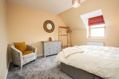 a bedroom with a bed and a chair and a mirror at Carreg Wen in Harlech