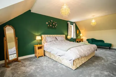 a bedroom with a large bed and a green wall at Carreg Wen in Harlech