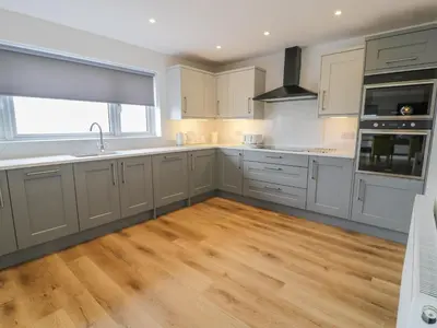 a kitchen with white cabinets and a wooden floor at Melin Y Plas in Barmouth
