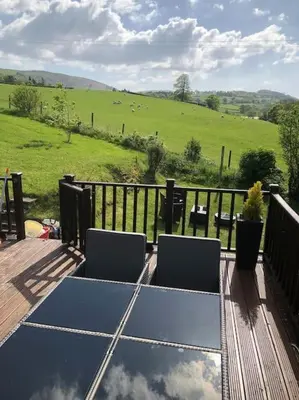 a table and chairs on a deck with a view of a field at 5f Stanley Lodge, Caer Beris, Builth Wells - No tradesman in Builth Wells
