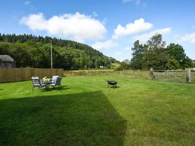 a patio with two chairs and a table in a yard at Ty-Ucha Cottage in Llangollen