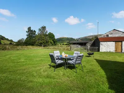 a table and chairs in a grass field at Ty-Ucha Cottage in Llangollen