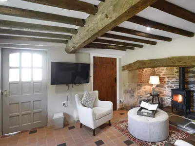 a living room with a tv and a chair and a fireplace at Ty-Ucha Cottage in Llangollen
