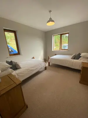 a bedroom with two beds and two windows at Llety Cynnes in Machynlleth
