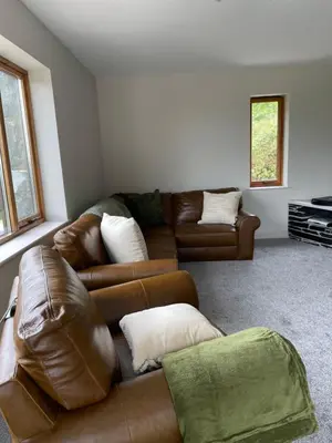 a living room with a brown leather couch at Llety Cynnes in Machynlleth